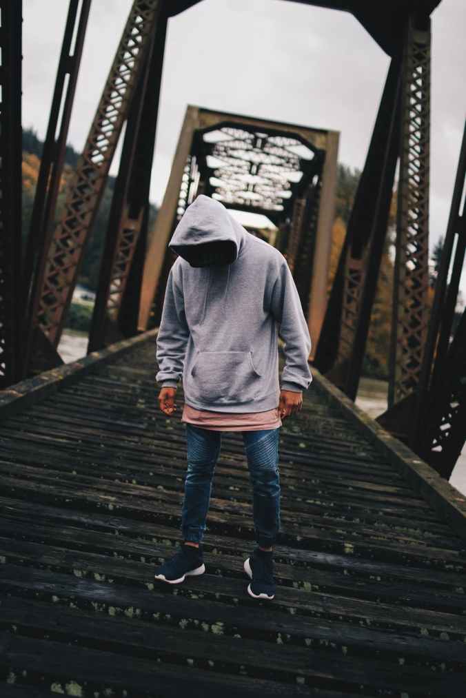 man in gray pull over hoodie standing on train rail